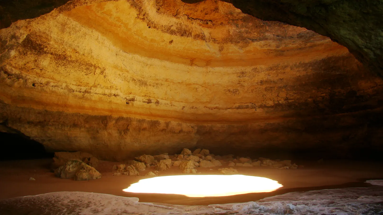 The Benagil sea cave on the Algarve, sunlight falling through the round hole in the roof onto the sand