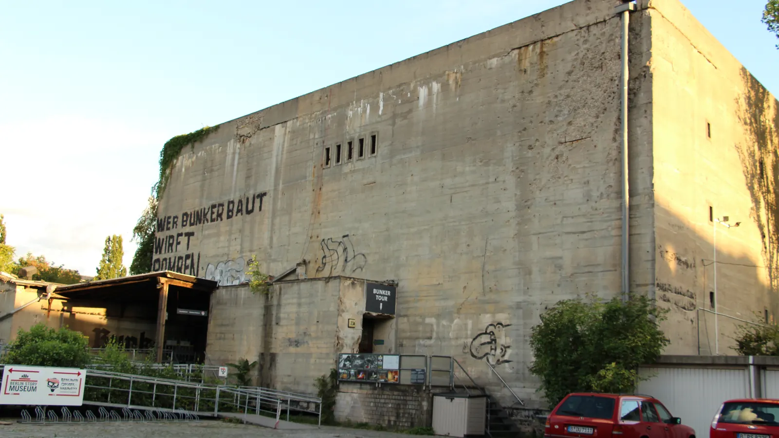 A bare concrete corridor in a Berlin air-raid shelter, cables running along the ceiling