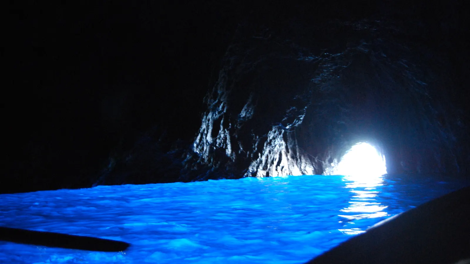 Glowing blue water inside the Blue Grotto on Capri, the bright entrance arch behind
