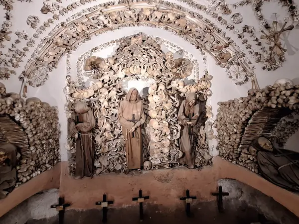 Arches of pelvic bones and a niche of robed skeletons in the Crypt of the Pelvises inside the Capuchin Crypt in Rome.