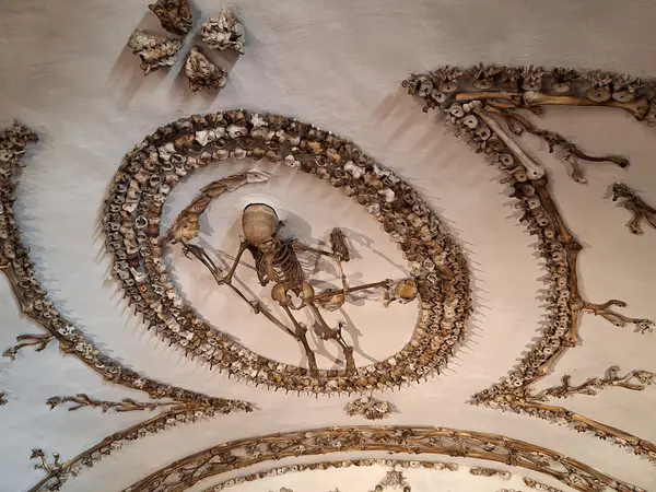 A child's skeleton holding a scythe and scales on the ceiling of the Crypt of the Three Skeletons in the Capuchin Crypt.