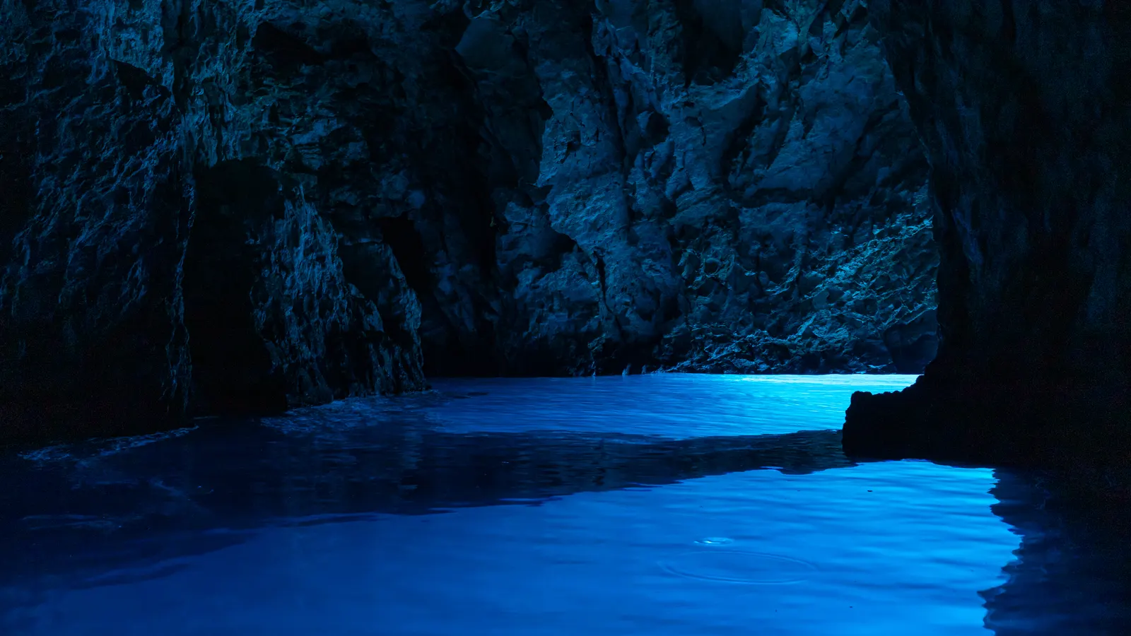 Blue light filling the water inside the Blue Cave on the island of Biševo in Croatia