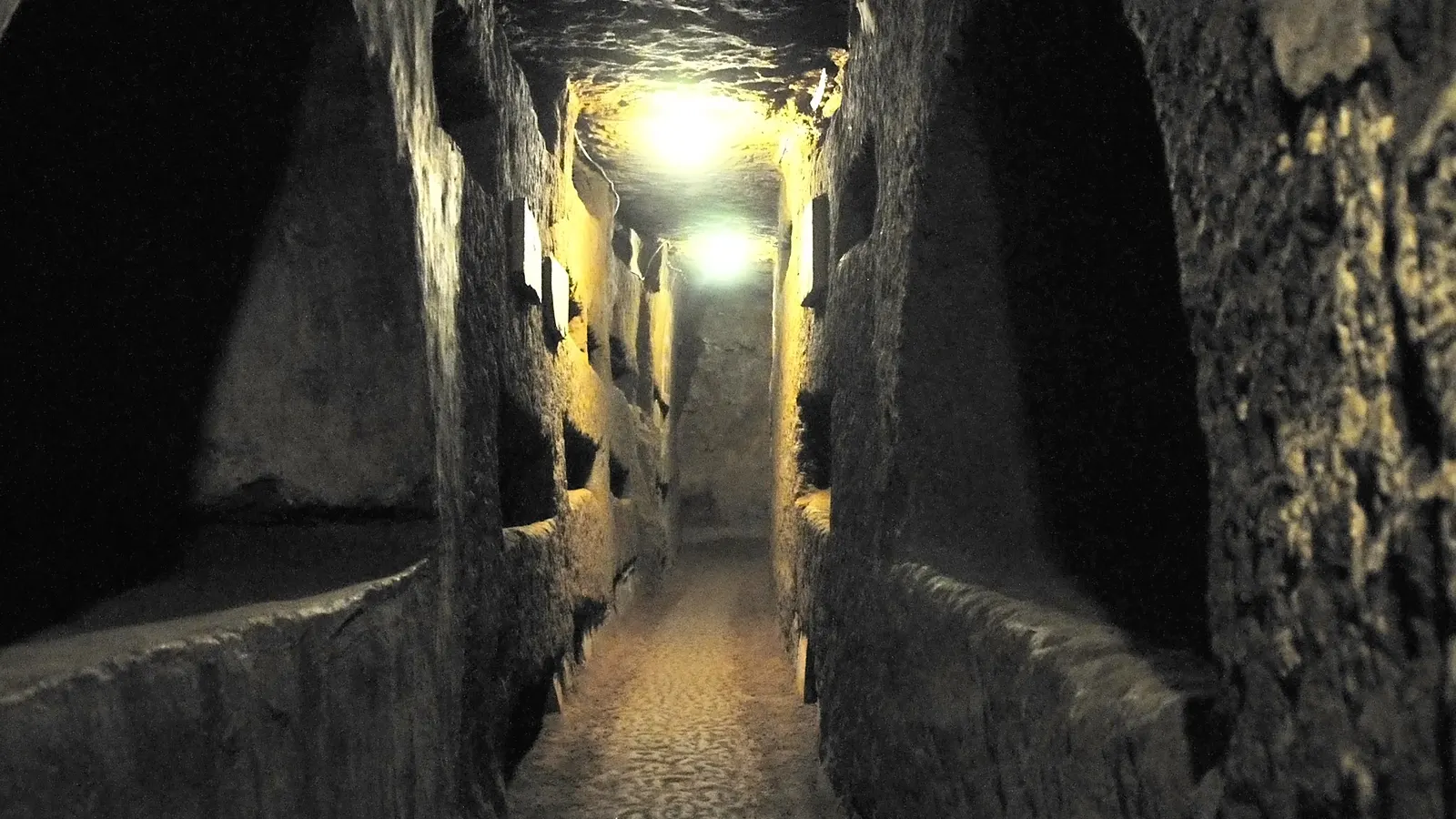 A narrow gallery lined with burial niches in the Domitilla catacombs in Rome