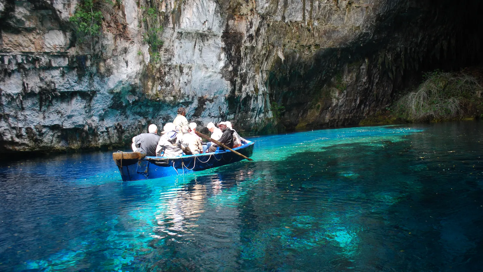 A rowing boat with visitors on the turquoise water of the Melissani cave lake on Kefalonia