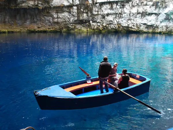 A boatman rows visitors across the brilliant blue water of Melissani Cave lake on Kefalonia.
