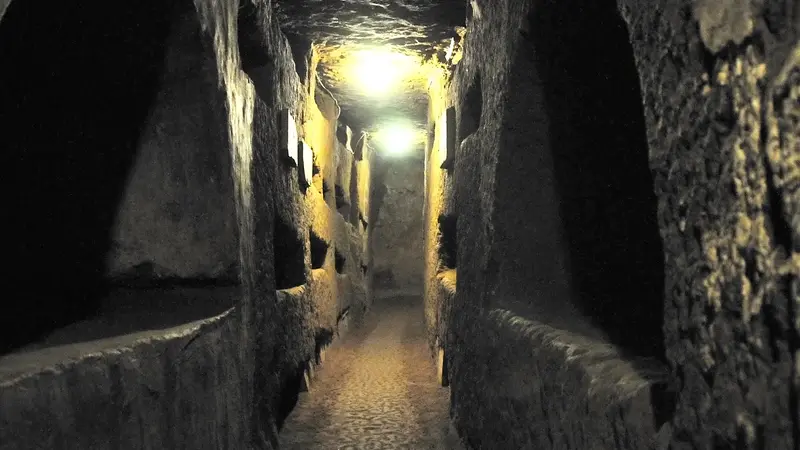 A narrow gallery lined with burial niches in the Domitilla catacombs in Rome