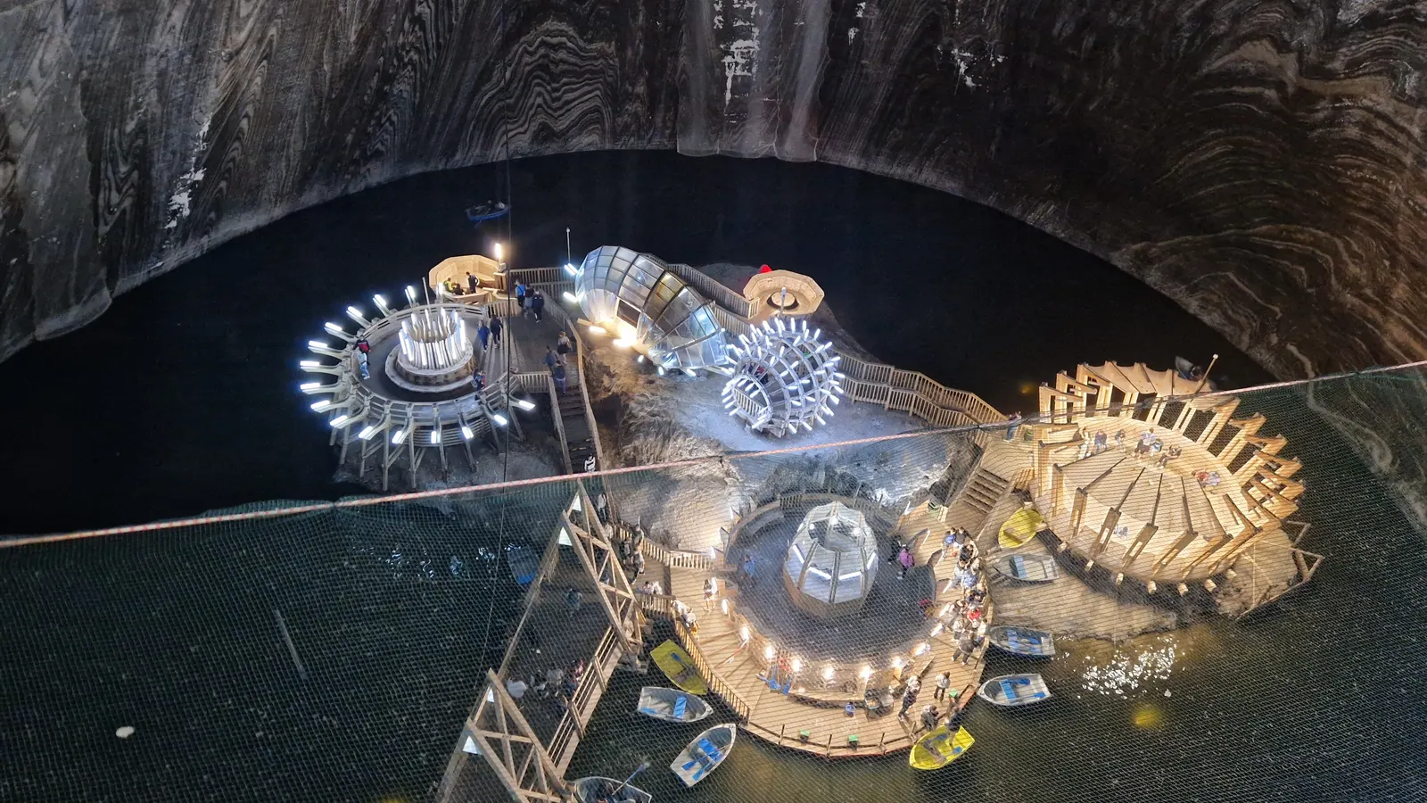 The lit shaft of Salina Turda with its wooden walkways and the underground lake far below